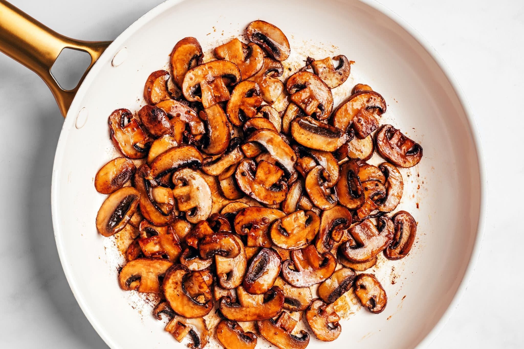 A full skillet of sliced cremini mushrooms cooked until deeply browned and caramelized, with golden edges and very little visible moisture remaining in the pan.