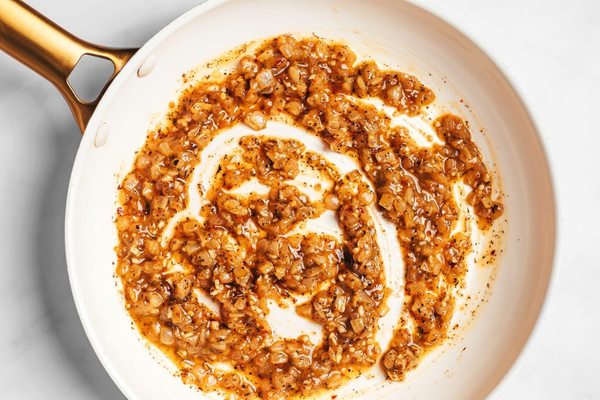 Cooked onions, garlic, herbs, and red pepper flakes coated in melted butter and flour to form a thick, golden roux across the bottom of the skillet.