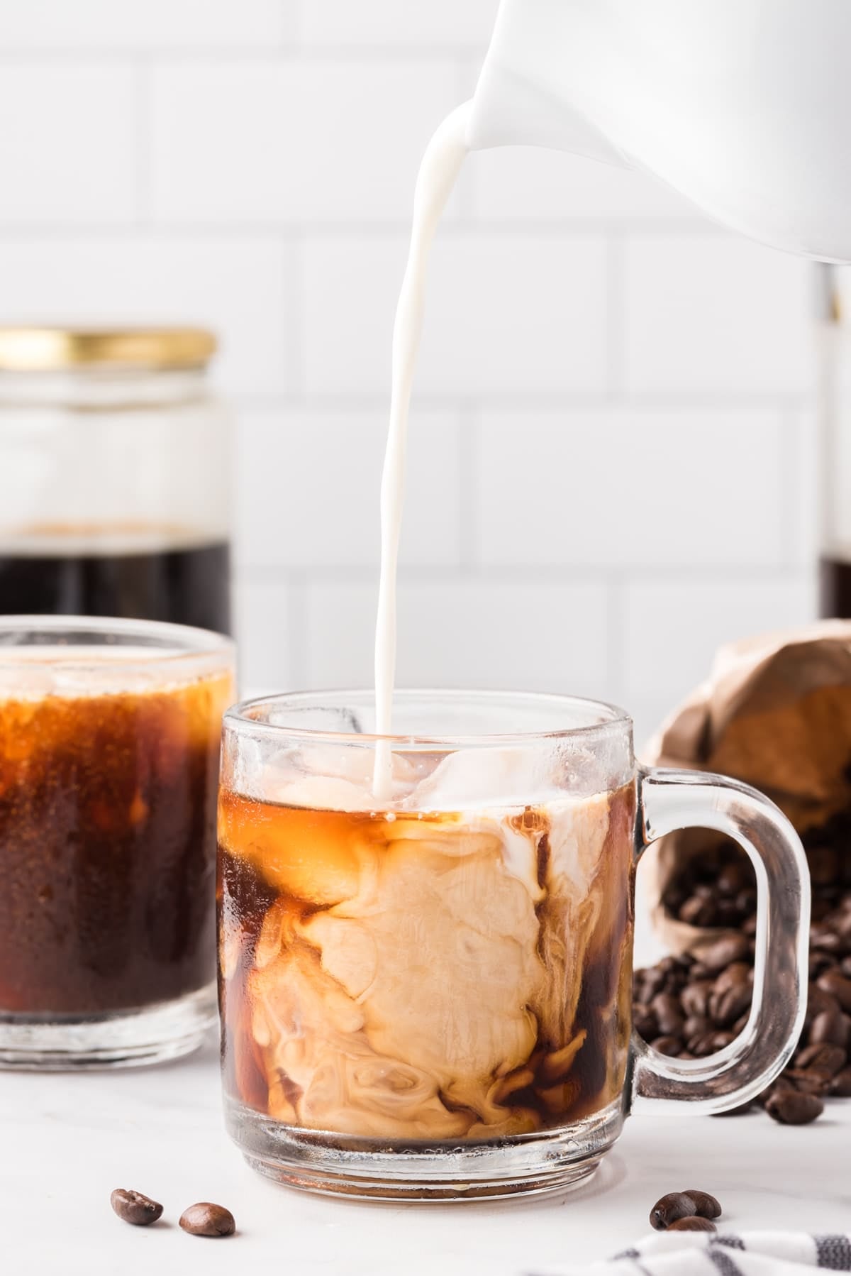 Image showing milk being poured into a glass coffee mug filled with iced cold brew coffee.