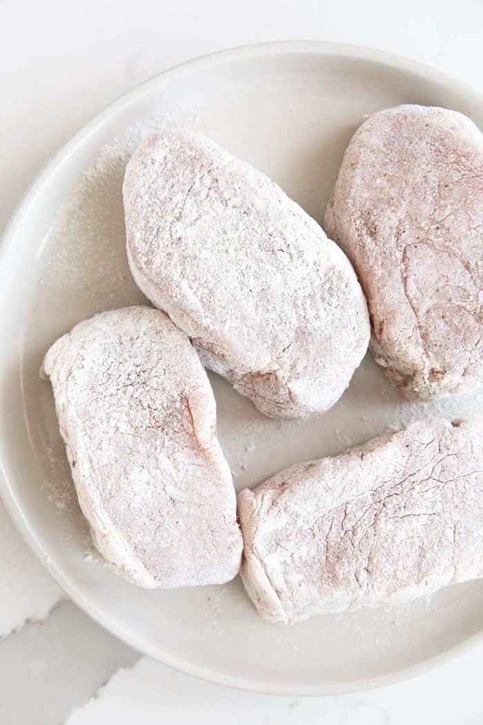 Image of four thick-cut boneless pork chops coated with flour.