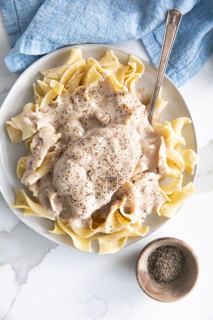 Overhead image of a plate filled with egg noodles and topped with a large pork chop with mushroom gravy.