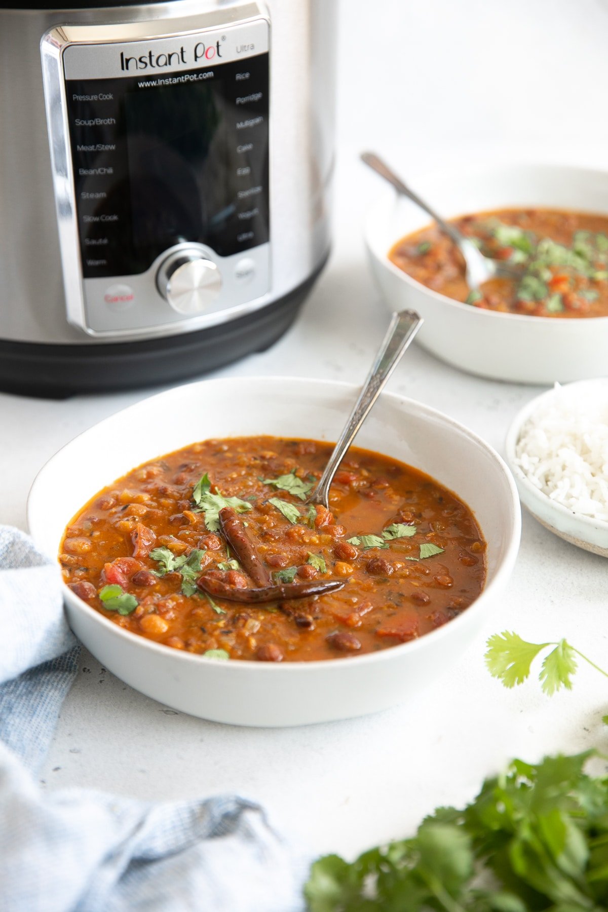 Image of two white bowls filled with fully cooked and prepared chana masala garnished with cilantro.