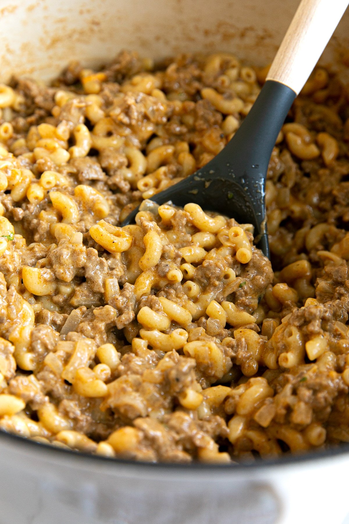 Large white ceramic Dutch oven filled with homemade hamburger helper made with ground beef and macaroni noodles.