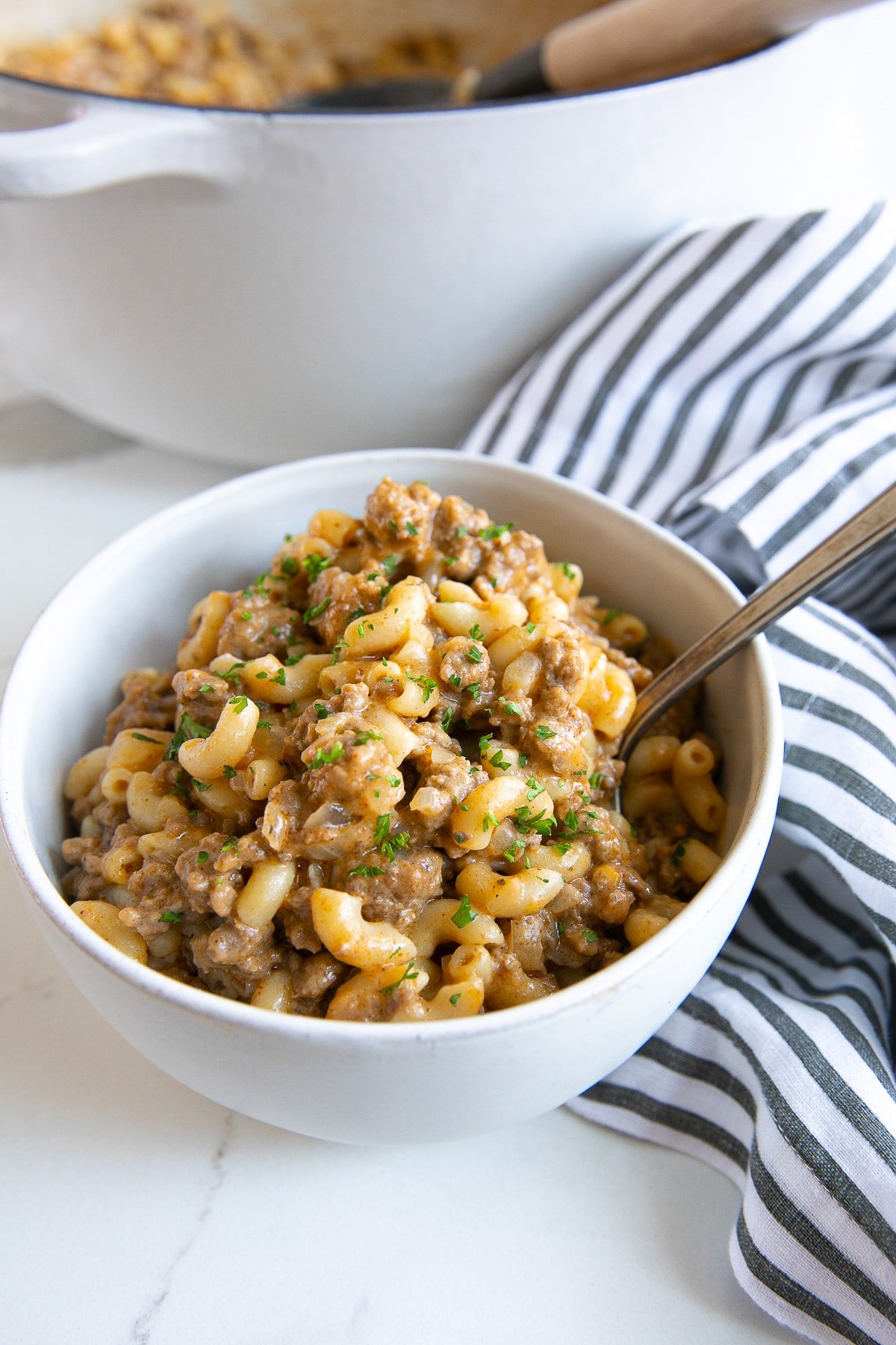 Image of a white bowl filled with homemade one-pot hamburger helper and garnished with minced parsley.