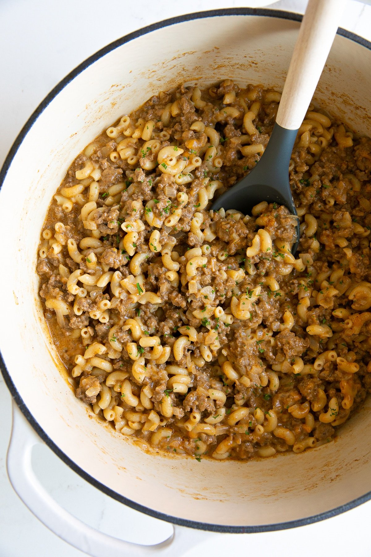 Large white ceramic Dutch oven filled with homemade hamburger helper made with ground beef and macaroni noodles.