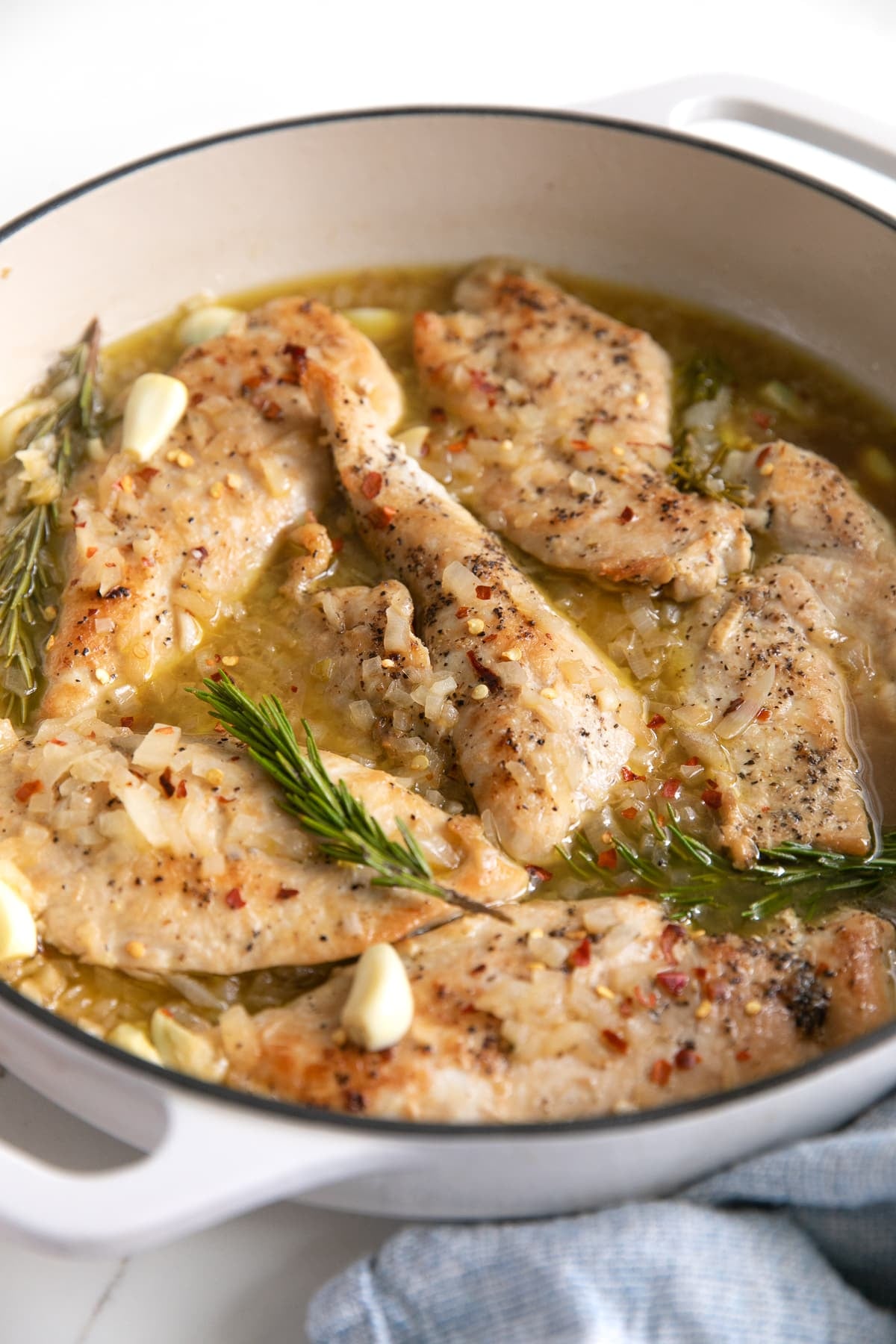 Garlic and rosemary chicken in a large white pan.