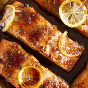 Close-up overhead image of four equal-sized cooked salmon covered in a homemade honey garlic sauce.