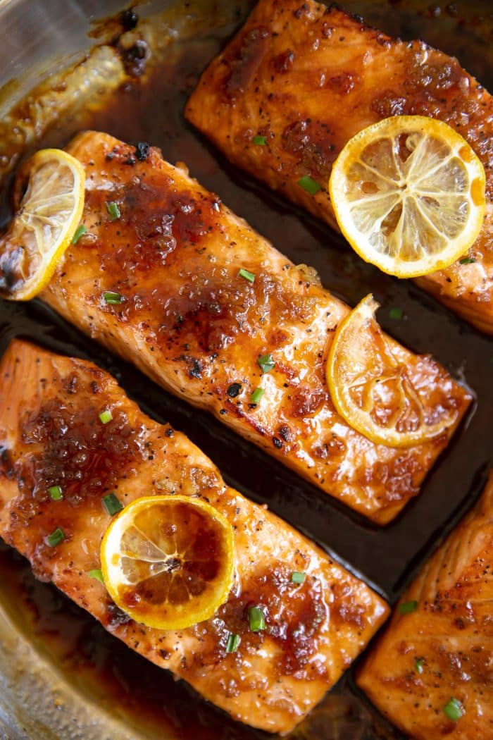 Close-up overhead image of four equal-sized cooked salmon covered in a homemade honey garlic sauce.