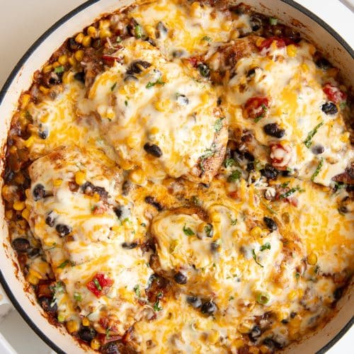 Large skillet filled with thinly sliced chicken breasts cooked and covered with a mixture of onions, black beans, tomatoes, and sweet corn and smothered in melted cheese.