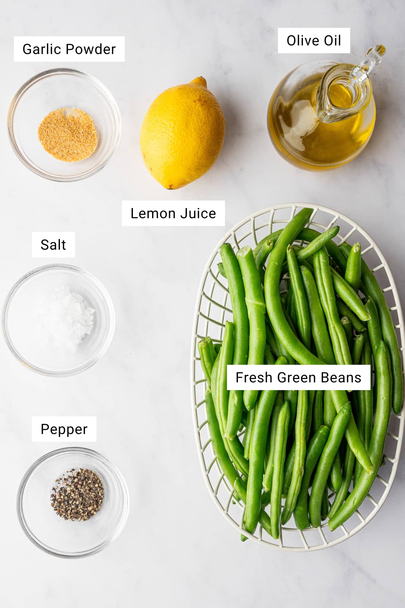Ingredients for air fryer green beans including fresh green beans, olive oil, garlic powder, lemon, salt, and pepper.
