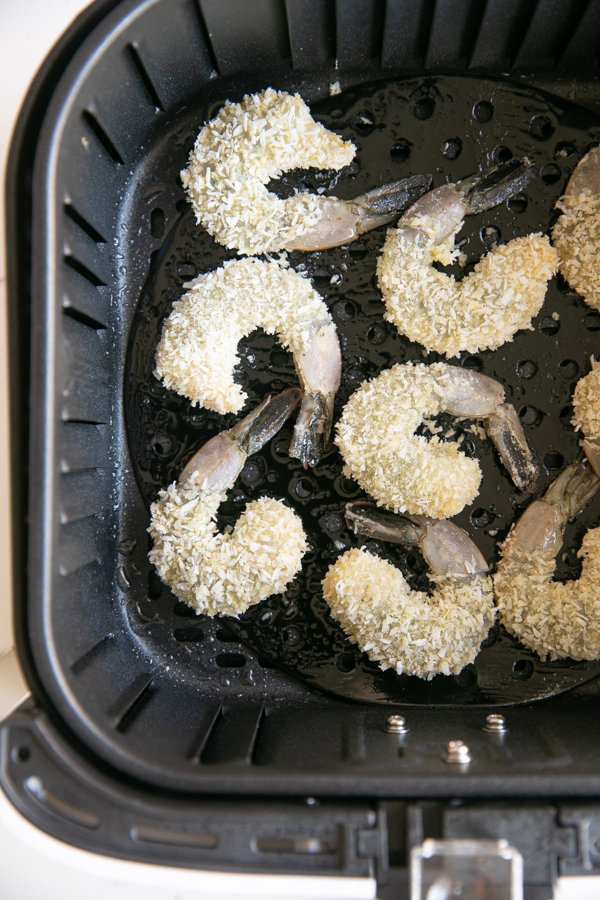 Raw shrimp dipped in egg and covered in flour and shredded coconut.