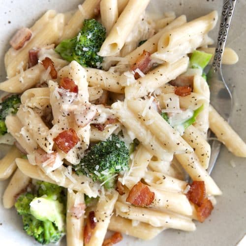 Image of a plate filled with bacon and broccoli pasta penne tossed in a homemade cream sauce.