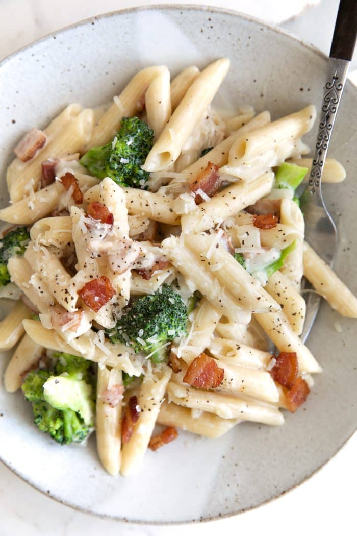 Image of a plate filled with bacon and broccoli pasta penne tossed in a homemade cream sauce.