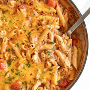 Overhead image of a large white ceramic skillet filled with cheesy turkey pasta.