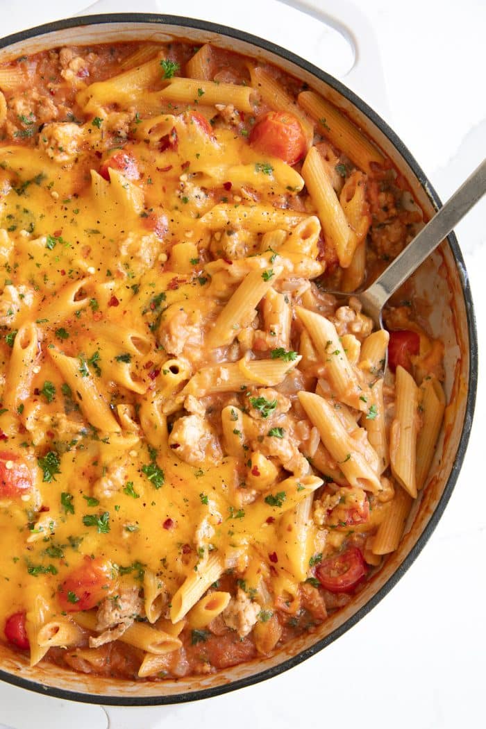 Overhead image of a large white ceramic skillet filled with cheesy turkey pasta.