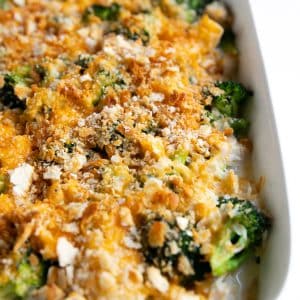 Large white baking dish filled with homemade chicken broccoli rice casserole topped with melted cheddar cheese and golden buttery crackers.