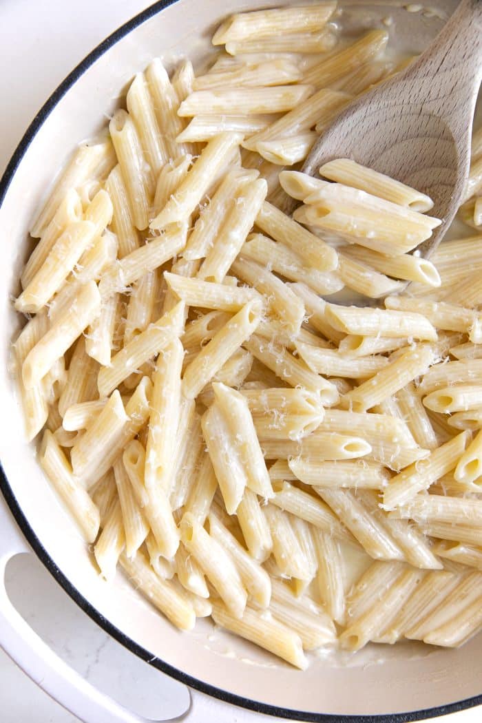 Overhead image of a white pan filled with creamy penne pasta.