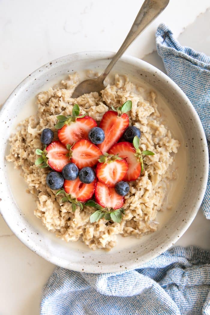 Overhead image of a large shallow bowl filled with oatmeal that's been cooked in the Instant Pot and has been topped with fresh strawberries and blueberries and drizzled with milk.