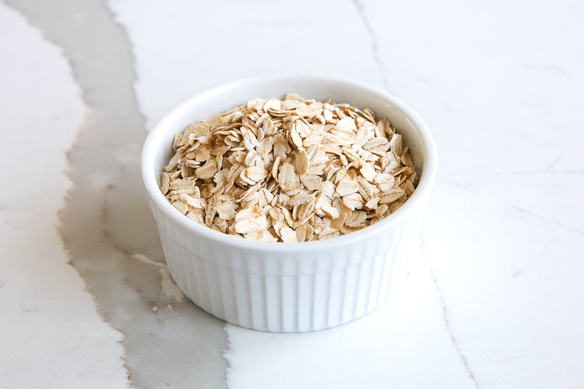 Small white ramekin filled with old fashioned rolled oats.