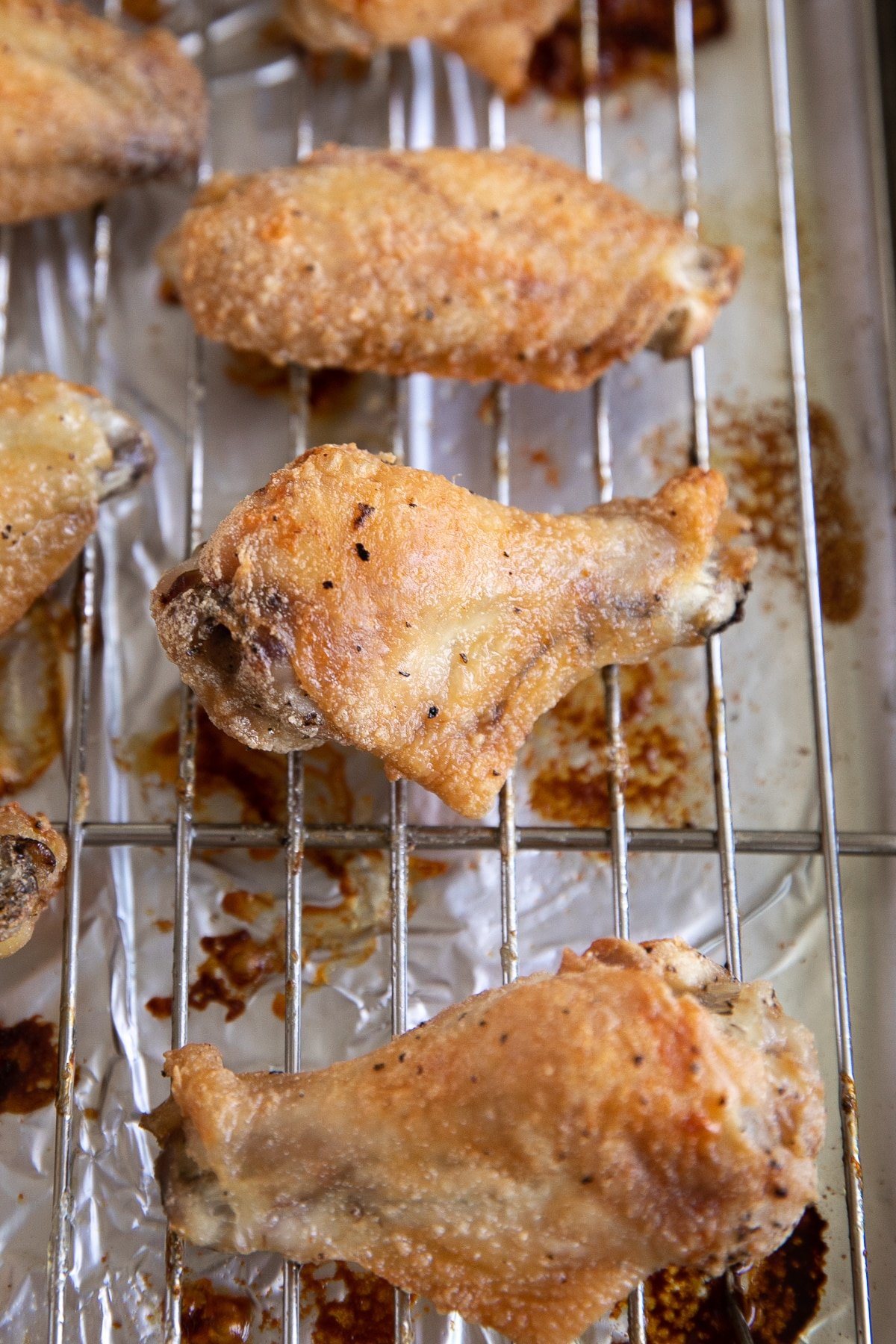 Image of crispy baked chicken wings on a wire baking rack before being tossed in homemade buffalo sauce.