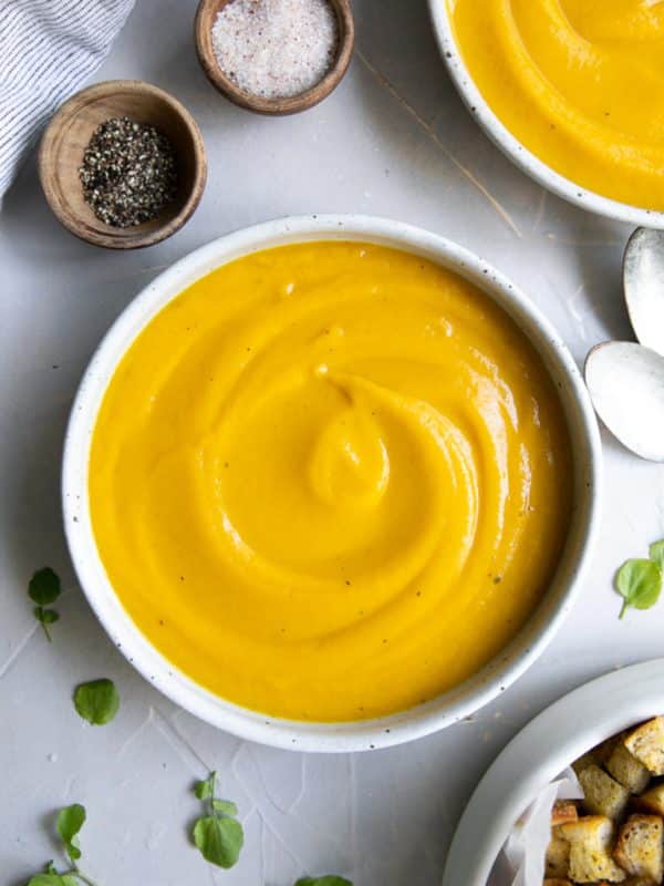 Shallow bowl filled with smooth and creamy, blended butternut squash soup.