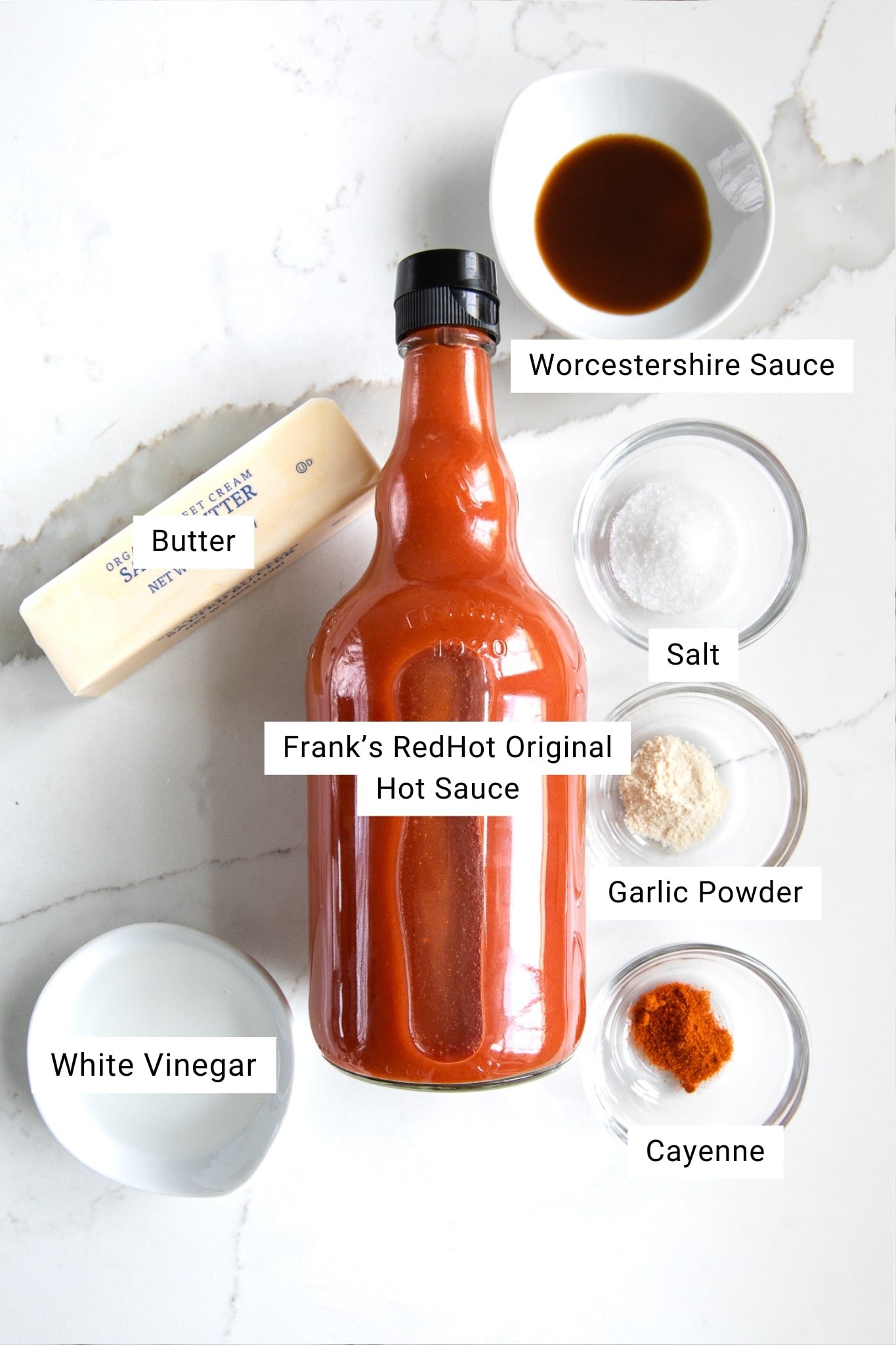 Labeled ingredient photo showing Frank’s RedHot Original hot sauce, butter, Worcestershire sauce, white vinegar, salt, garlic powder, and cayenne pepper for making homemade buffalo wing sauce.