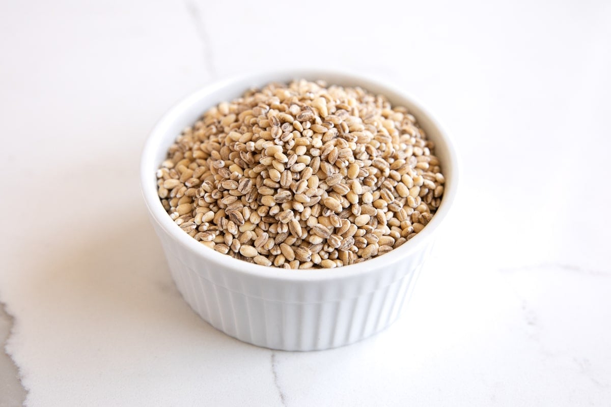 White ramekin filled with uncooked hulled barley.