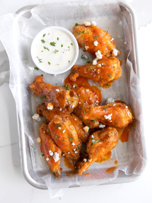Overhead image of air fryer buffalo chicken wings on a small tray garnished with blue cheese..
