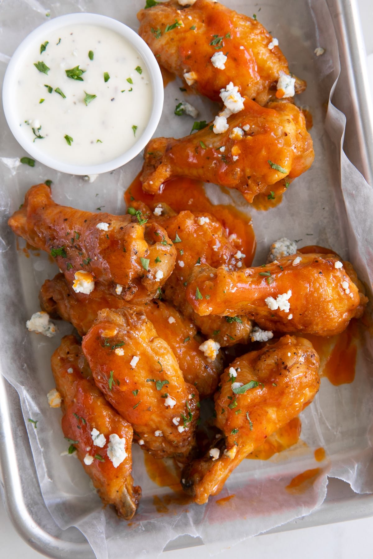 Overhead image of air fryer buffalo chicken wings on a small tray garnished with blue cheese..