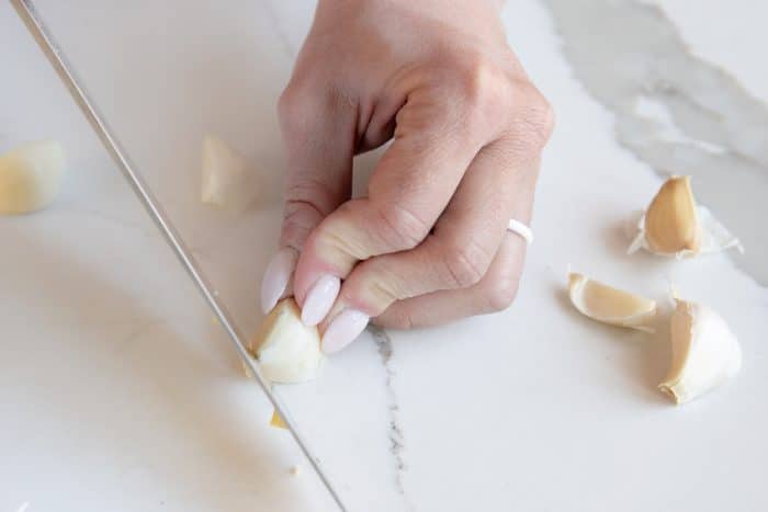 Trimming the ends from a single clove of garlic.