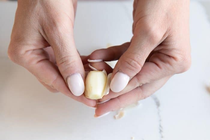 Removing the peel from one clove of garlic.