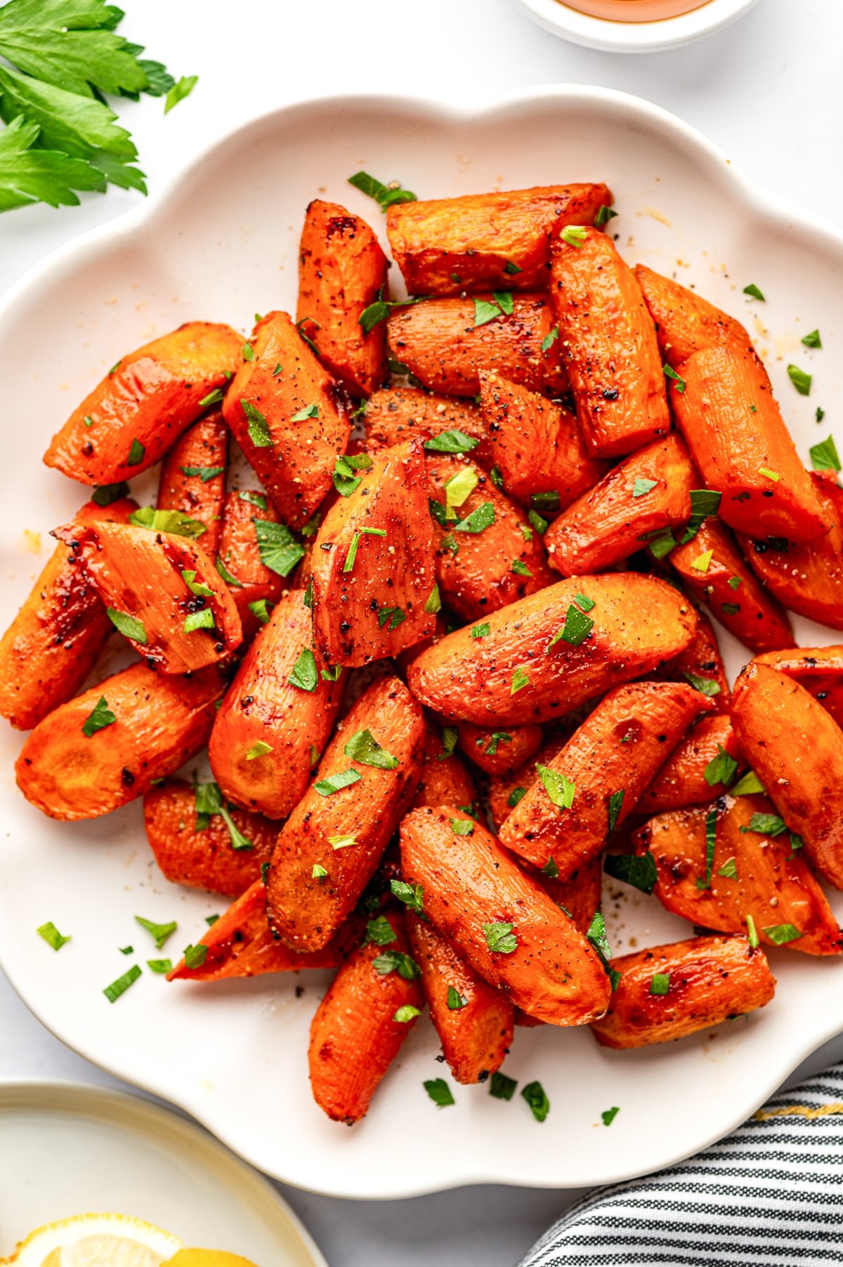 Overhead close-up of roasted carrots piled on a white serving plate.