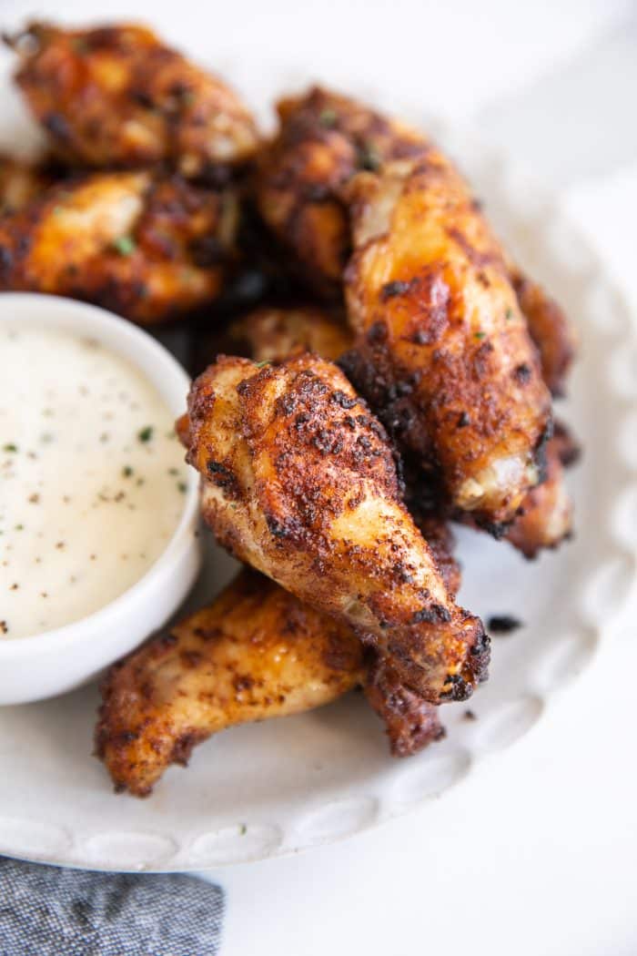 White plate with crispy air fryer chicken wings and a side of ranch dressing.