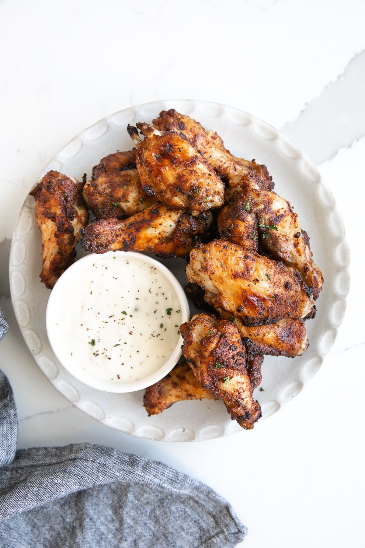 Overhead image of a white plate with crispy air fryer chicken wings and a side of ranch dressing.