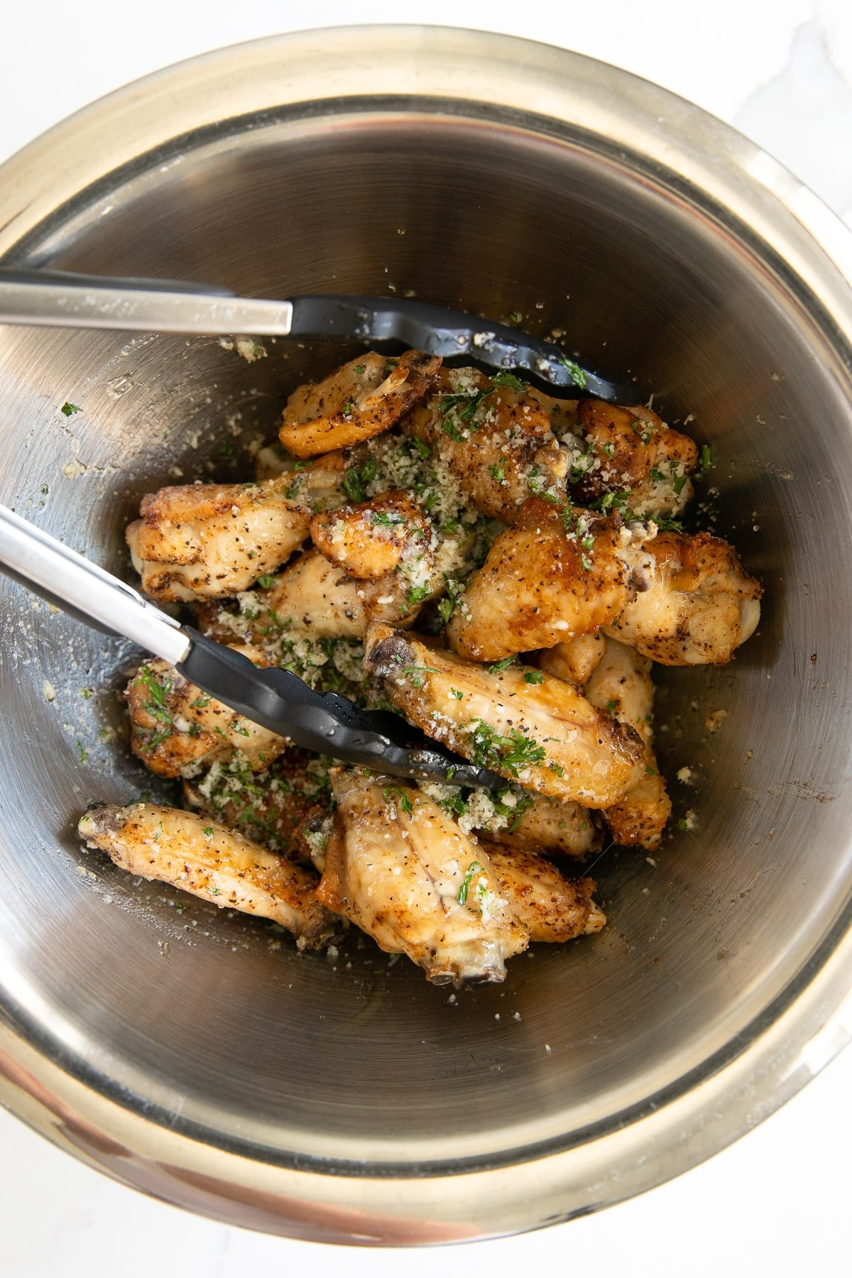 Mixing bowl filled with crispy baked chicken wings tossed in a garlic parmesan sauce.