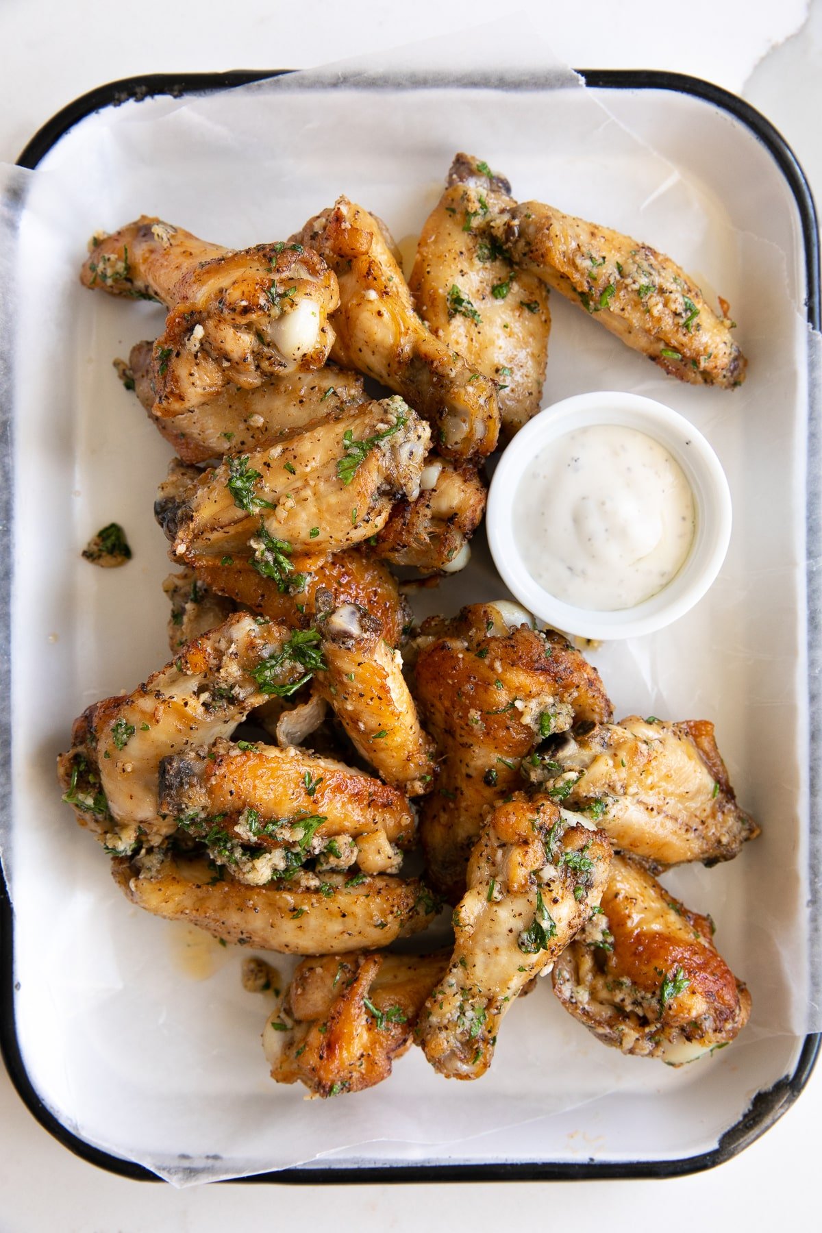 Serving tray topped with crispy baked garlic parmesan wings and served with a side of ranch dressing.