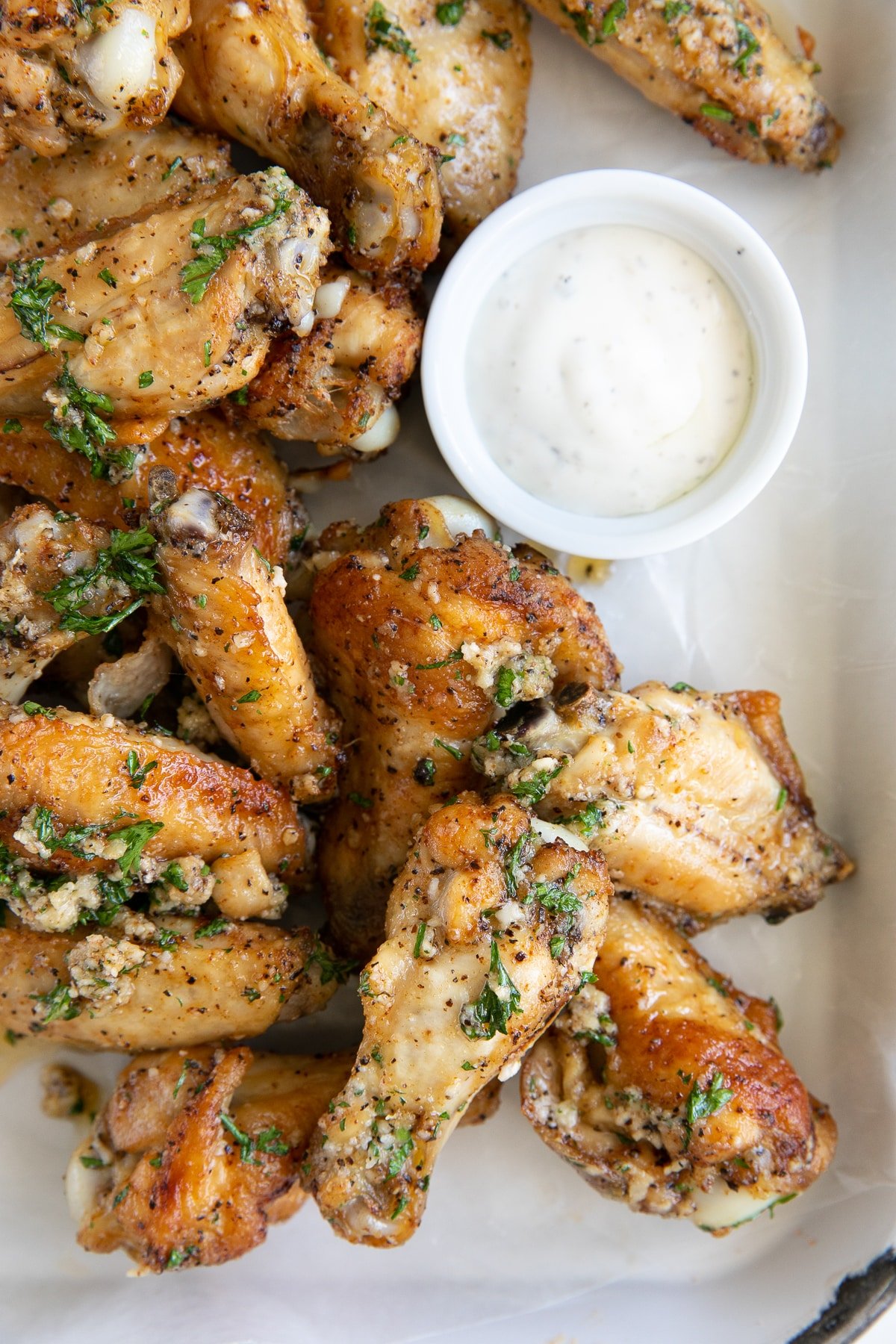 Overhead image of crispy baked chicken wings and drumettes covered in a homemade garlic parmesan sauce.