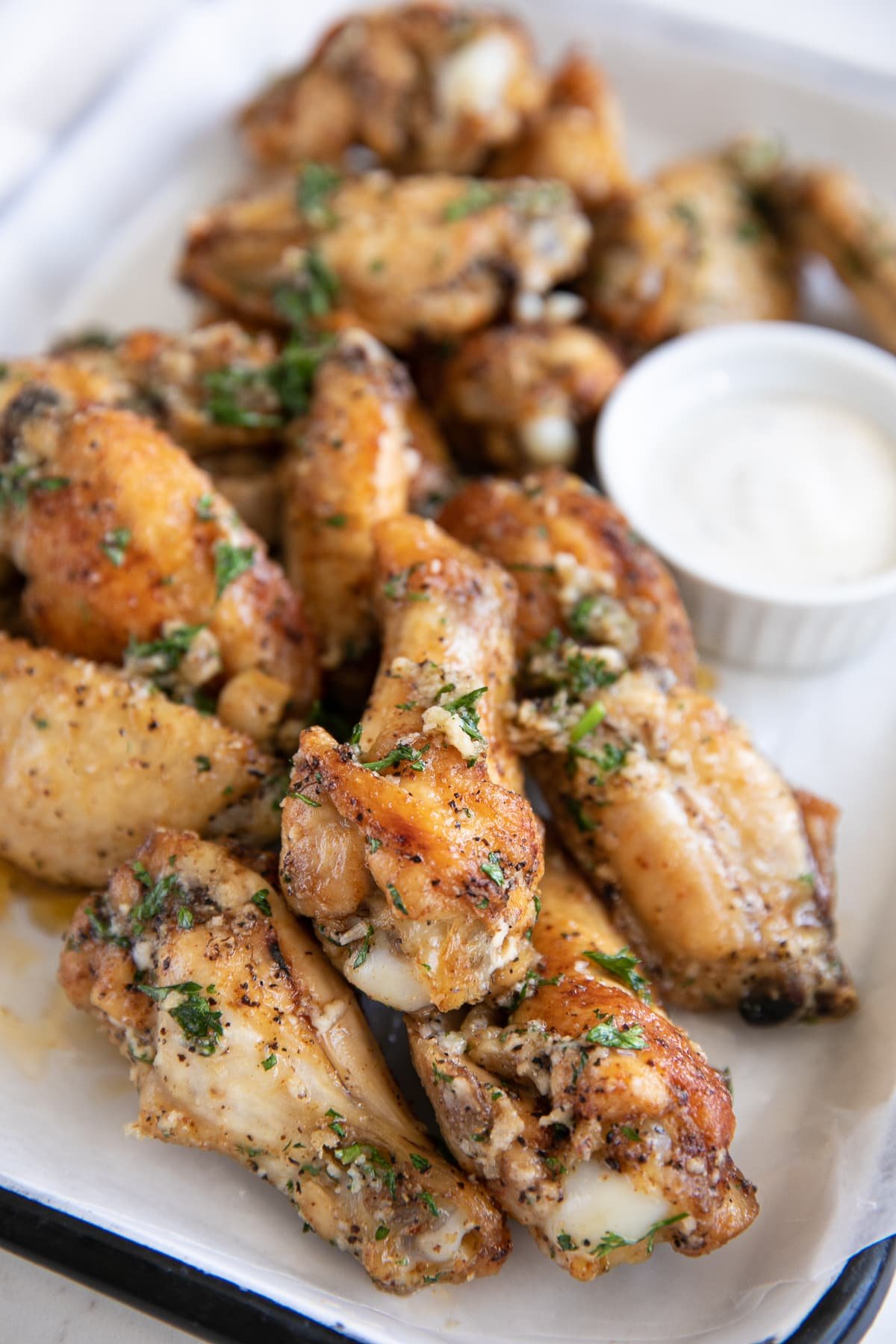 Close up image of garlic parmesan wings on a small white serving tray.