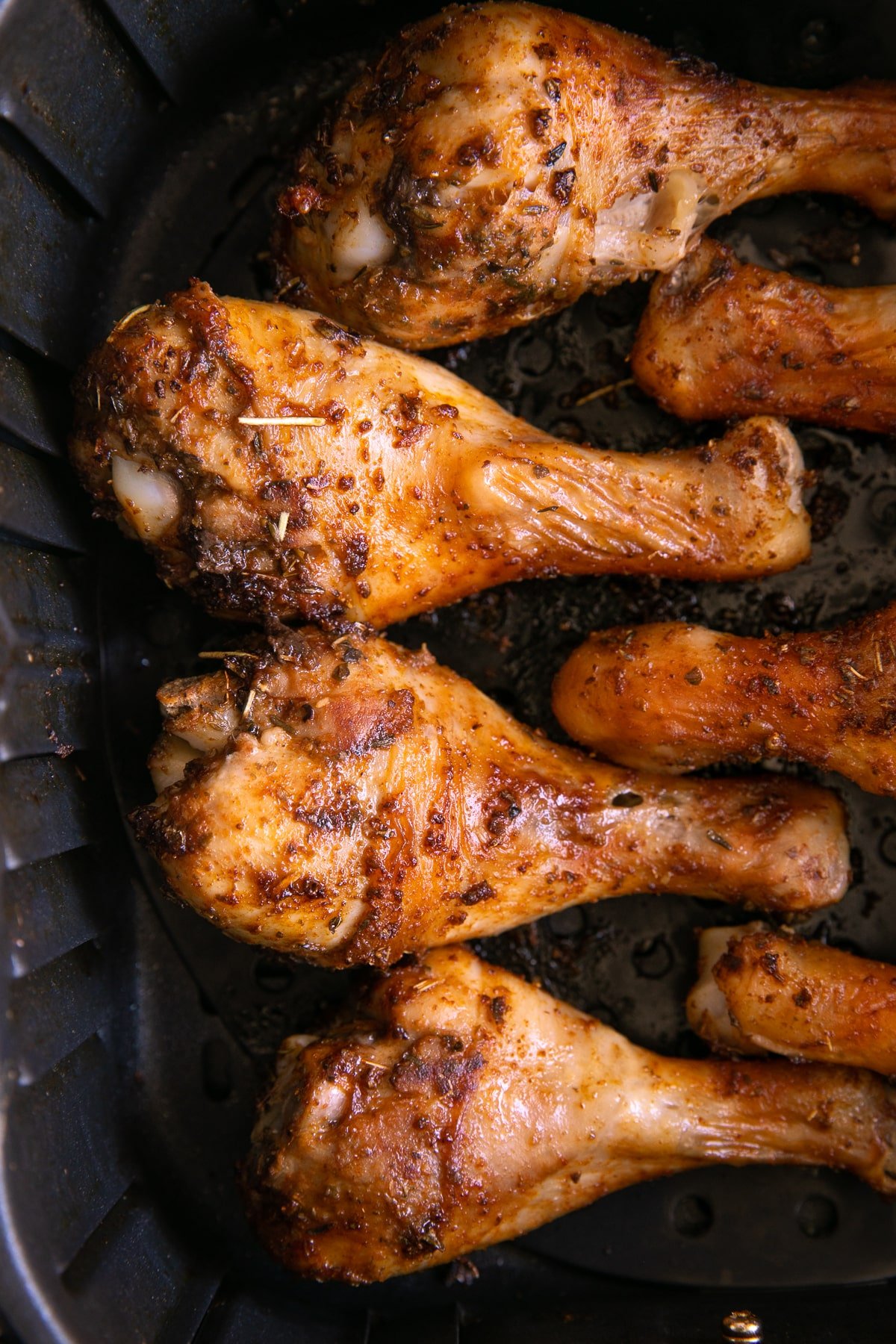 Fully cooked and well seasoned air fryer chicken legs still in the air fryer basket.