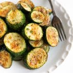 Small white plate filled with roasted zucchini with parmesan cheese.