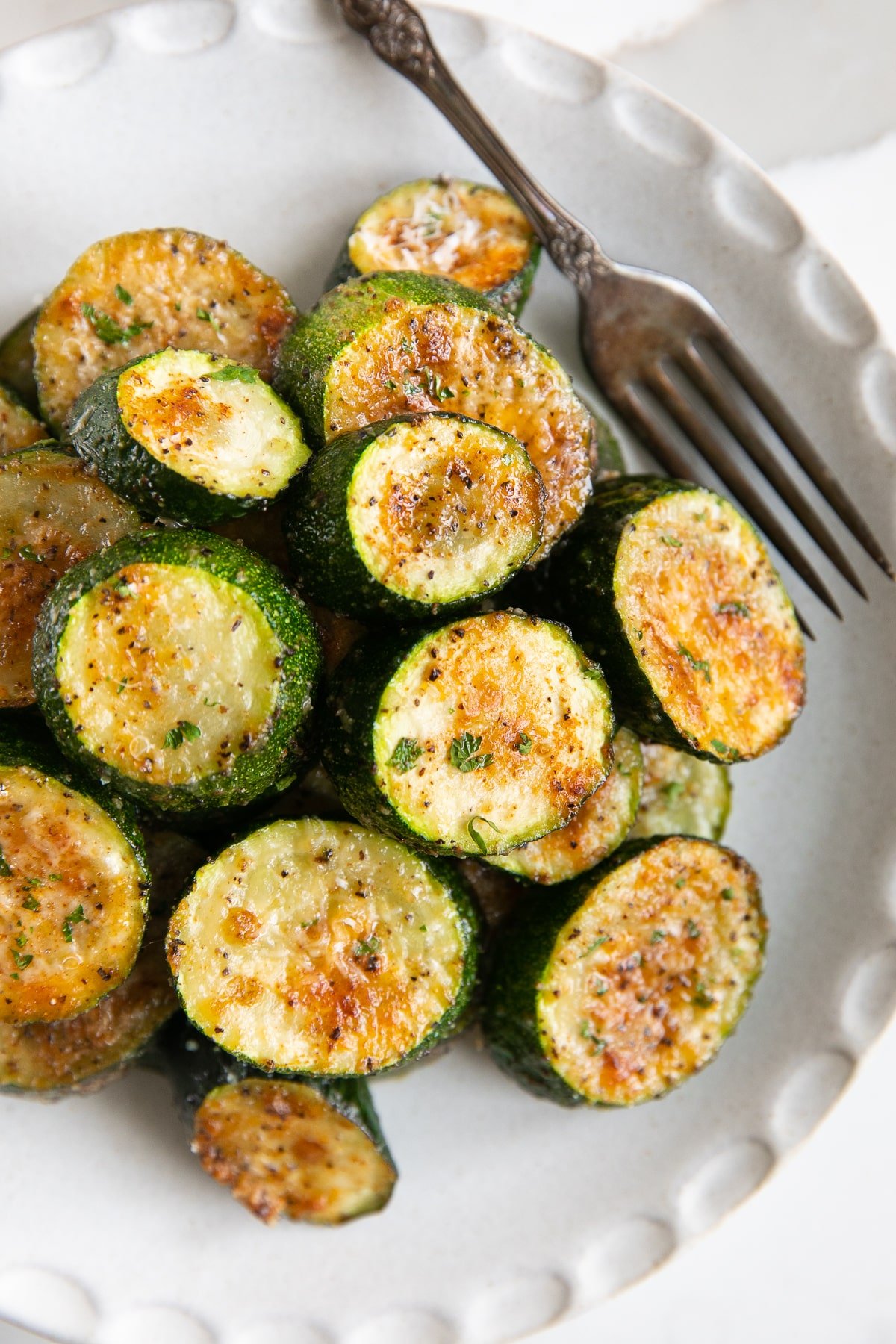 Small white plate filled with roasted zucchini with parmesan cheese.