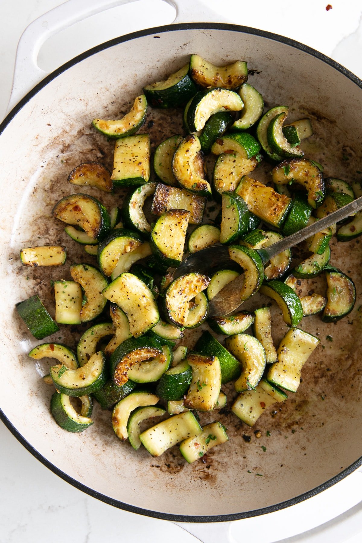 White pan filled with tender sauteed zucchini with garlic and butter.