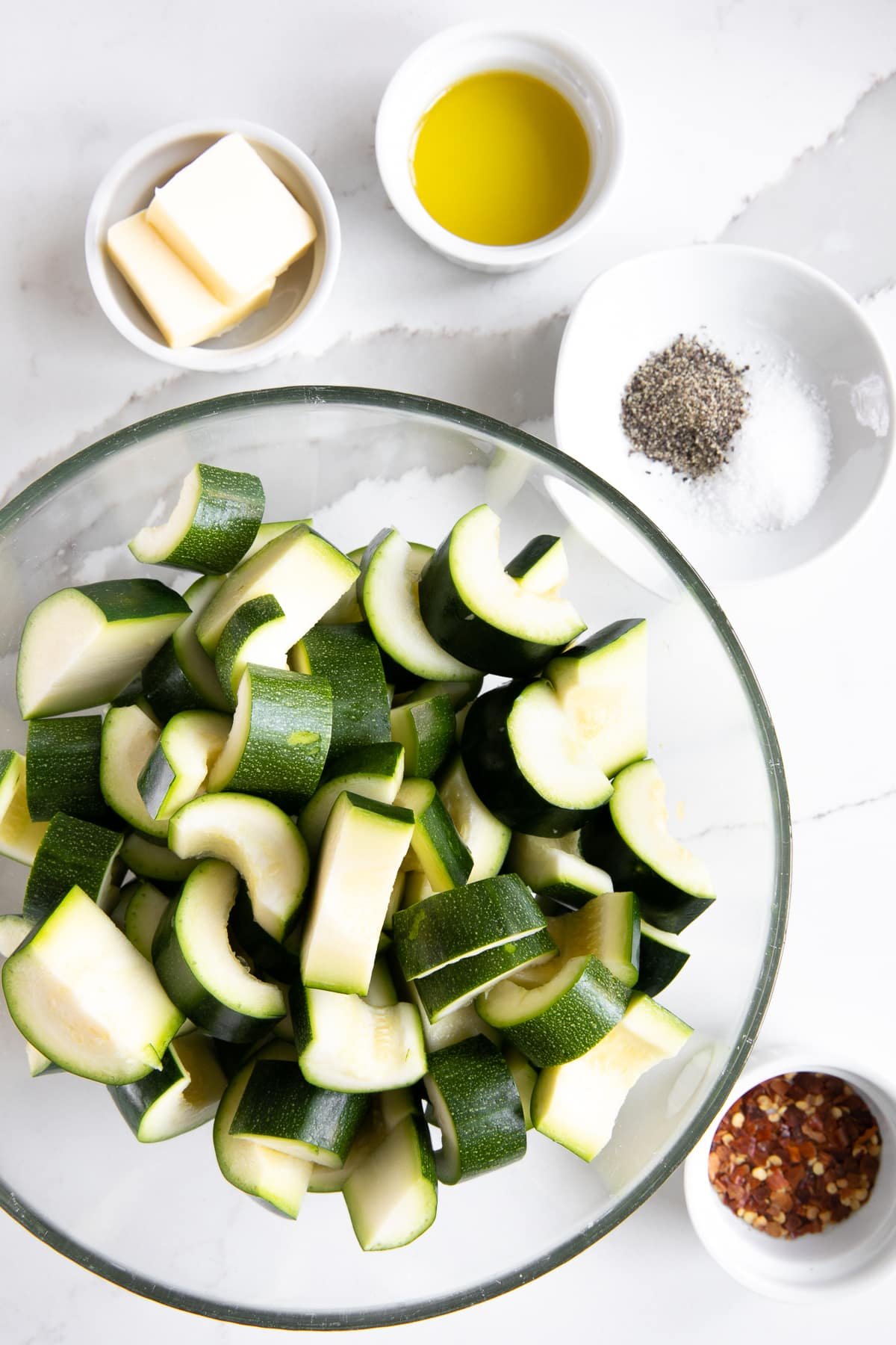 Ingredients needed to make sauteed zucchini in their own small serving bowls.