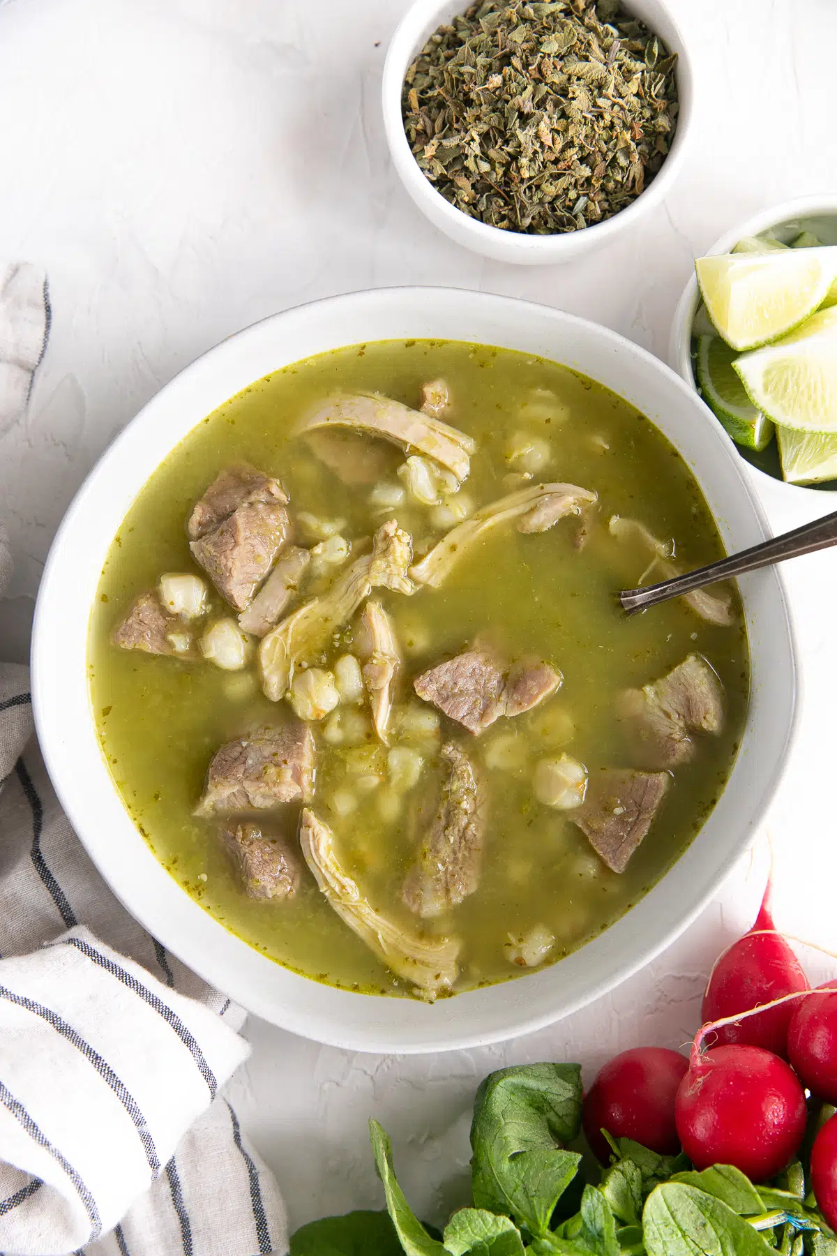 Bowl filled with green pozole made with chicken and pork.