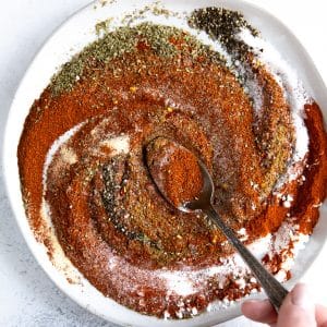 Shallow white bowl filled with various different seasonings mixing together.