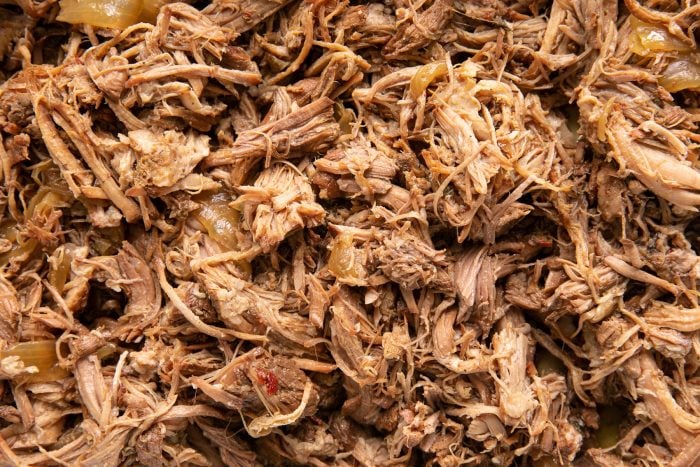 Shredded pulled pork carnitas on a large baking sheet.