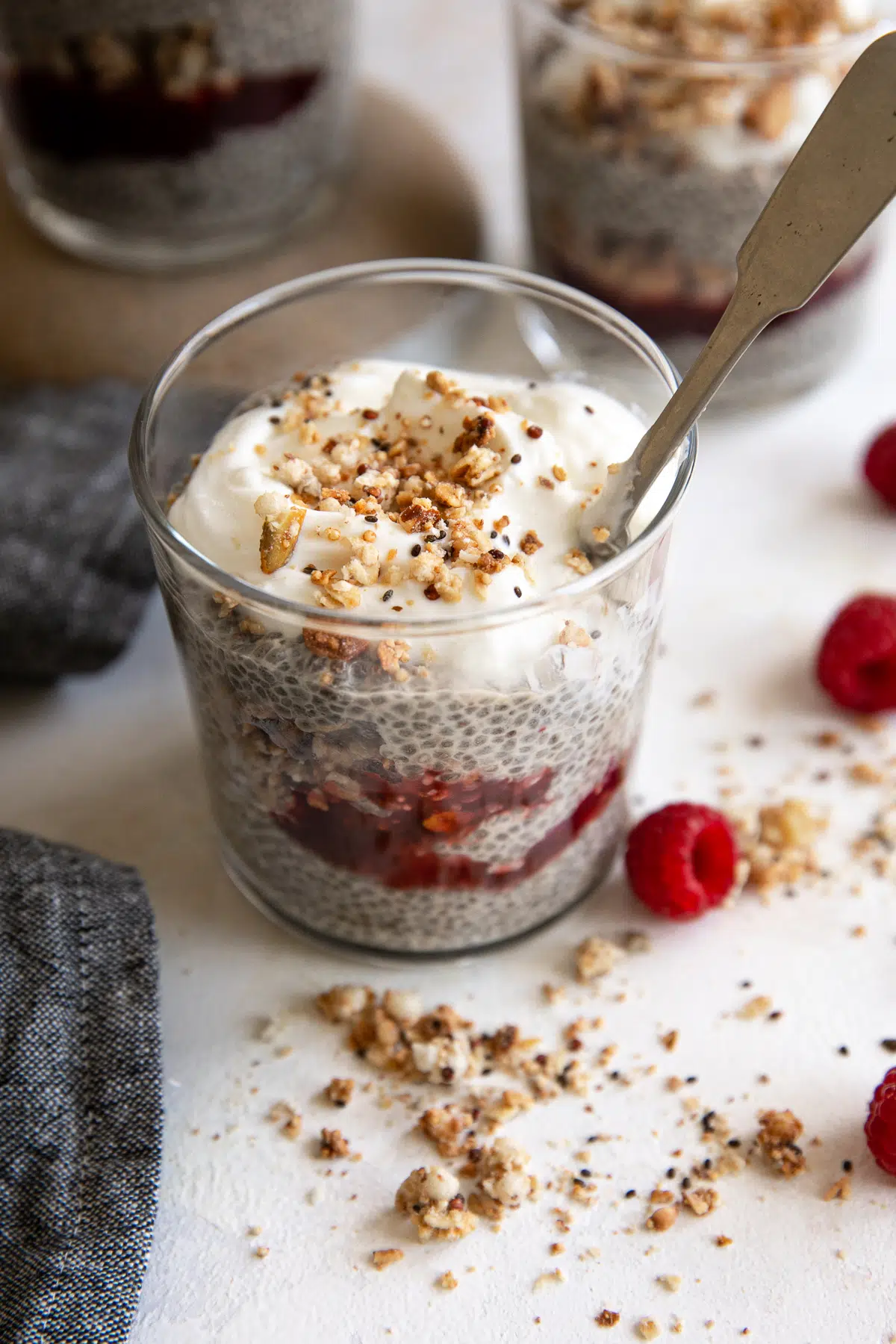 Image of a glass jar filled with vanilla chia seed pudding flavored with raspberry jam and granola.