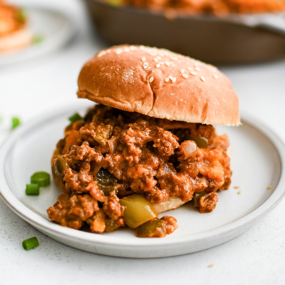 Homemade sloppy joe mixture sandwiches between a toasted hamburger bun.