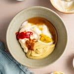 All the key ingredients—mayonnaise, Dijon mustard, yellow mustard, honey, white vinegar, hot sauce, cayenne, and salt—are added to a small mixing bowl in preparation for whisking.