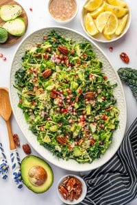 Finished Brussels sprout salad on an oval platter with lemon wedges and avocado